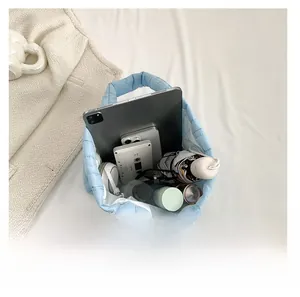 Intérieur spacieux d'un sac cabas matelassé bleu clair contenant tablette, téléphone et casque