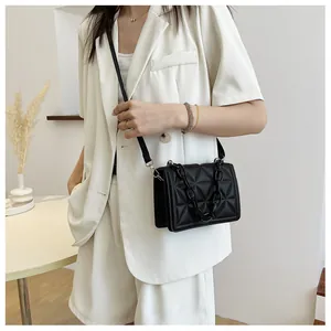 Detail of black quilted crossbody bag with thick acrylic chain on casual outfit