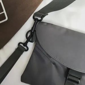 Détail d'un sac bandoulière en nylon gris avec boucle noire et sangle amovible