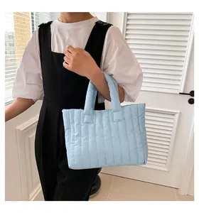 Gros plan d'un sac cabas matelassé bleu clair avec rayures verticales porté par un mannequin