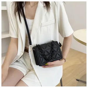Detail of black quilted crossbody bag with thick acrylic chain and slim shoulder strap
