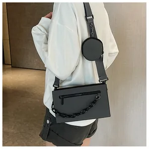 Detail of dark grey crossbody bag with decorative black chain and mini round pouch