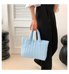 Détail du sac cabas matelassé bleu clair avec rayures et poignées souples rembourrées