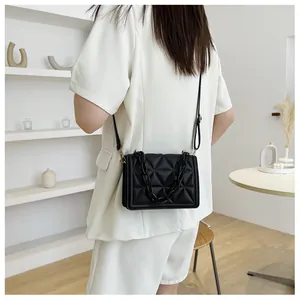 Detailed view of black quilted crossbody bag with chunky acrylic chain on model