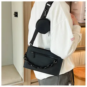 Detail of black crossbody envelope bag with decorative chain and small round pouch