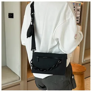 Detail of black rectangular crossbody bag with chain and detachable round coin purse