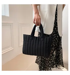 Détail d'un sac cabas noir matelassé avec texture rembourrée verticale et finition nylon