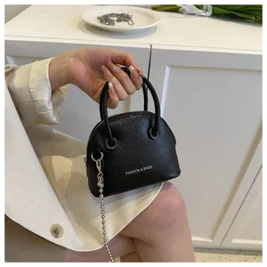 Detail of black litchi pattern mini shell bag with silver ball chain and top handles