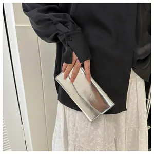 Silver mirror-finish envelope wallet held by a model for a modern minimalist style