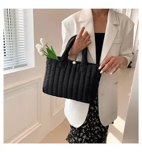 Vue détaillée du sac cabas matelassé noir avec rayures verticales et fermoir magnétique doré
