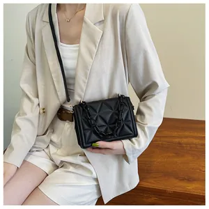 Detail of black quilted crossbody bag with stylish thick acrylic chain handle on model
