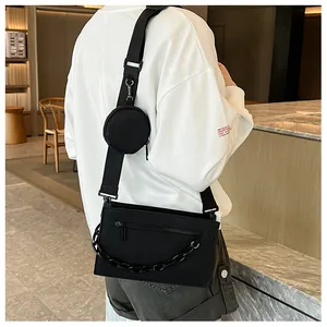 Detail of black crossbody bag with decorative chain and small round pouch attachment