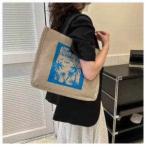 Detail of beige woven tote bag with blue California print and black shoulder strap