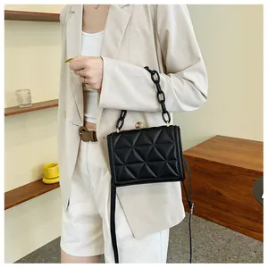 Detail of black quilted shoulder bag with chunky acrylic chain and leather strap