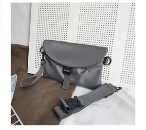 Détail d'un sac bandoulière gris en nylon avec boucle frontale et sangle ajustable