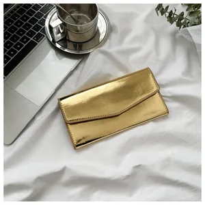 Detail of a golden mirror finish envelope wallet on a white textured background