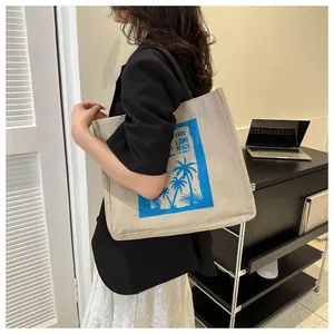 Detail of large canvas tote bag with palm tree print and black woven shoulder strap