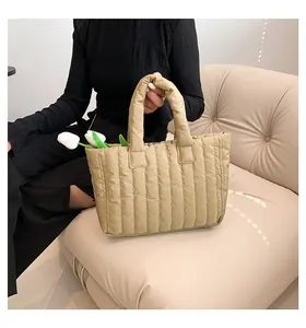 Détail du sac cabas matelassé kaki avec rayures verticales sur canapé beige