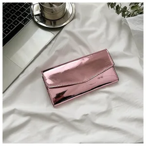 Metallic pink envelope clutch wallet with quilted edges on a minimalist white fabric