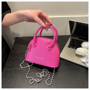 Detail of fuchsia litchi texture leather mini shell bag with silver bead chain
