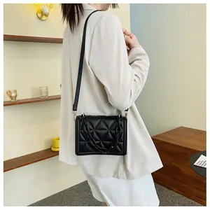 Detail of black quilted shoulder bag with acrylic chain strap on a lifestyle model