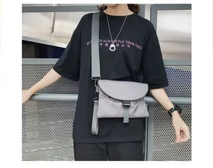 Photo street style d'un sac bandoulière en nylon gris avec large sangle et boucle de fermeture