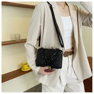 Close-up of quilted black crossbody bag with acrylic chain and amber buckle detail