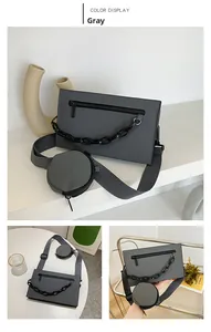 Detail of grey crossbody bag with round coin purse and thick black plastic chain strap