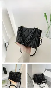 Detail of black quilted shoulder bag with acrylic chain handle and gold hardware