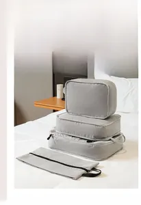 Detail of 4-piece gray travel storage cubes with zippers on a hotel bed setting