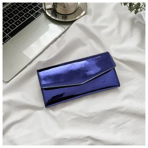 Flat lay of metallic purple envelope wallet on white fabric with laptop and coffee
