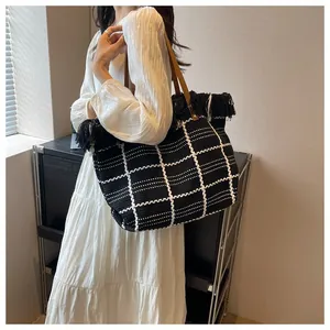 Macro view of woven checkered texture and black fringe on large knit tote bag