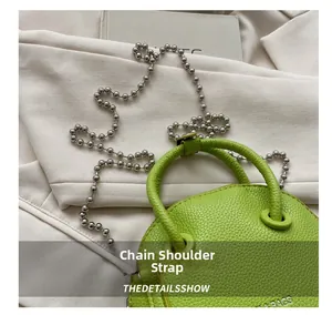Detail of lime green round bag showing litchi texture and silver ball chain strap
