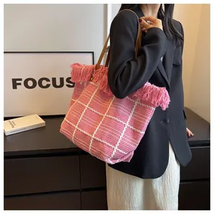 Detailed close-up of pink checkered knit tote bag with fringe edge and brown straps