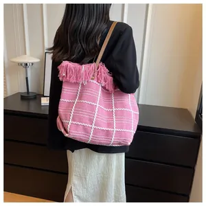 Detailed view of pink checkered woven tote bag with fringe trim and leather strap