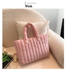 Détail du sac cabas matelassé rose avec rayures verticales sur un canapé blanc
