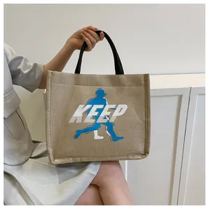 Detailed close-up of khaki canvas tote bag featuring blue runner print and KEEP logo design