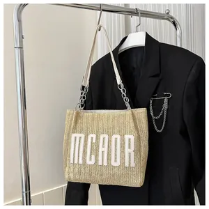 Detail of woven straw tote bag with MCAOR embroidery and white leather chain strap