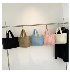 Série de sacs cabas matelassés en plusieurs coloris suspendus à un portant métallique