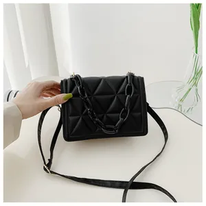 Detail of black quilted crossbody bag featuring a thick acrylic chain and gold hardware