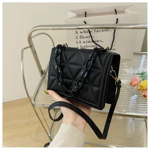 Detail of black quilted shoulder bag with acrylic chain and matte leather texture