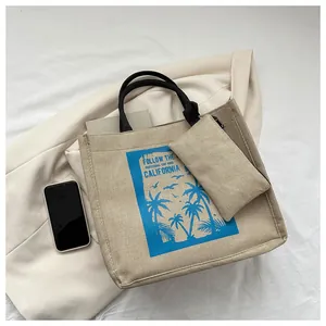 Detail view of beige canvas tote bag set with California beach print and black handles