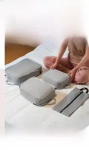 Comparison showing four grey compression travel organizers with mesh tops on a bed