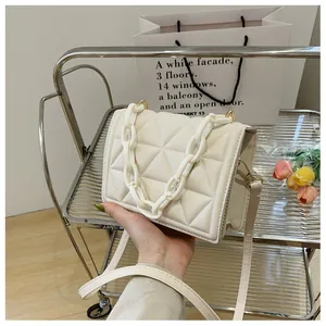 Close-up of cream square bag featuring triangular quilting and thick acrylic chain