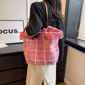 Pink checkered knit tote bag with fringe details and brown leather straps on model