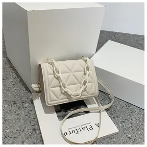 Close-up of beige quilted crossbody bag with stylish thick acrylic chain and flap closure