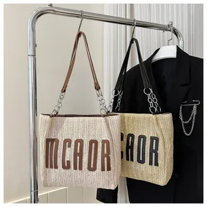 Detail of straw tote bag showing MCAOR letter design and metallic chain strap