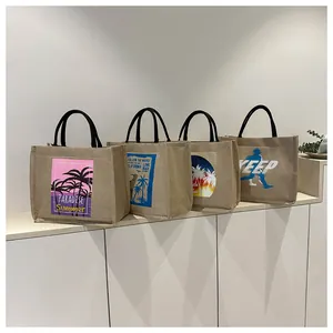 Set of four burlap tote bags with tropical palm prints and black handles on a white surface