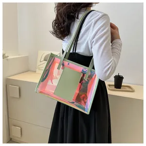 Detail of holographic pink PVC tote bag with green leather straps worn by a model
