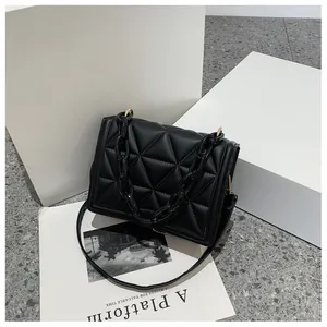 Detail of black quilted shoulder bag featuring thick acrylic chain and gold-tone hardware